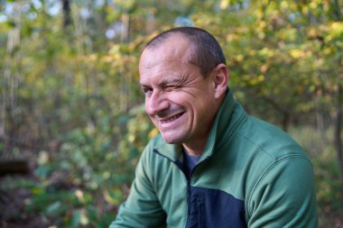 50 'lerinde gülümseyen olgun bir adam, değişik ifadeler sergiliyor.