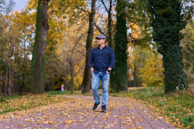 Gündüz vakti orta yaşlı bir adamın sonbahar parkında yürüyüşü 