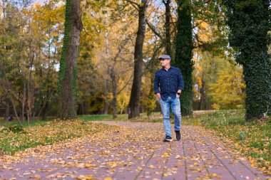 Gündüz vakti orta yaşlı bir adamın sonbahar parkında yürüyüşü 