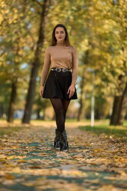 Parkta, etrafı renkli ağaçlarla çevrili genç İspanyol kadın. 