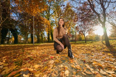 İspanyol güzel kadın sıcak bir günde etrafı renkli ağaçlarla çevrili parkta dinleniyor.