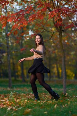 Gündüz vakti, ağaçlar ve yapraklarla çevrili, parkta güzel bir İspanyol kadını görüyorum.