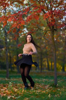 Gündüz vakti, ağaçlar ve yapraklarla çevrili, parkta güzel bir İspanyol kadını görüyorum.