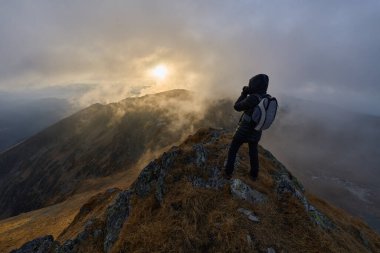 Sonbahar günü kayalık dağlarda engebeli patikada yürüyüş yapan bir kadın.