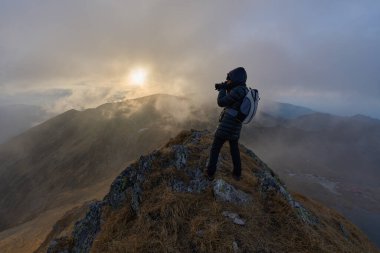 Soğuk bir sonbahar gününde kayalık dağlarda engebeli bir patikada yürüyüş yapan bir kadın.
