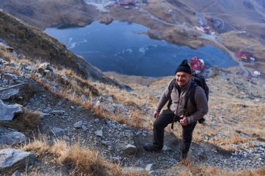 Kayalık dağlarda sırt çantasıyla yürüyüş yapan olgun bir yürüyüşçü.