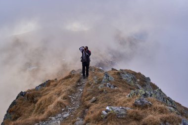 Kayalık dağlarda sırt çantasıyla yürüyüş yapan olgun bir yürüyüşçü.