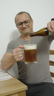 Mutlu orta yaşlı adam evde bira içiyor.