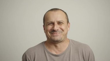 50 'li yaşlarındaki olgun bir adam yüksek sesle gülüyor, beyaz arka planda soyutlanmış.