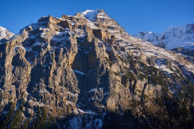 Soğuk, güneşli bir Kasım gününde, açık mavi gökyüzünün altında kar ile kaplanmış İsviçre Alplerinin manzarası.