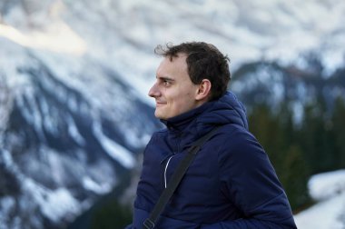 Genç adam arka planda İsviçre Alpleri ile tatil çekimi için poz veriyor.