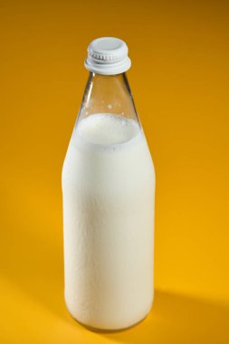 Sarı arka planda 500 mililitre taze inek sütü.