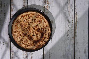 Tahta bir tabakta ince bir krep yığını servis edilmeye hazır.