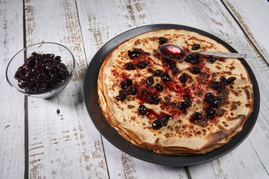 Tahtaya siyah kiraz reçeli konmuş ince krep yığını.