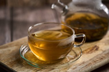 Japon Sencha çayını cam bardakta, kırsal bir tahta üzerinde cam çaydanlıkla yakından çek.