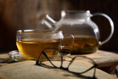 Japon Sencha çayını cam bardakta, kırsal bir tahta üzerinde cam çaydanlıkla yakından çek.