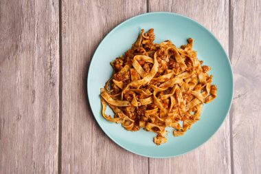 Tagliatelle 'li bolonez makarna ve ahşap bir tabakta kıyma.