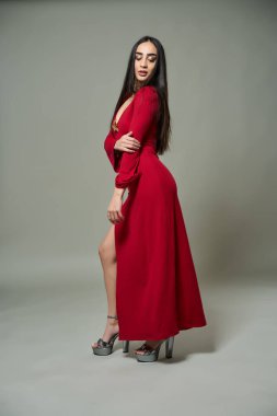 Gri arka planda kırmızı elbiseli çekici İspanyol kadın.