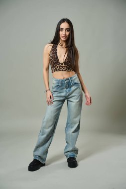 Platform ayakkabı giyen, leopar desenli bluzlu ve elmaslı kotlu çekici bir kadın.