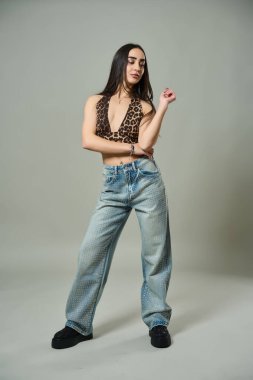 Platform ayakkabı giyen, leopar desenli bluzlu ve elmaslı kotlu çekici bir kadın.