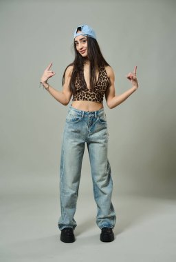 Leopar desenli bluz giyen güzel bir kadın, elmaslı kotlar ve kendine güvenen bir ifadeyle çömeliyor.