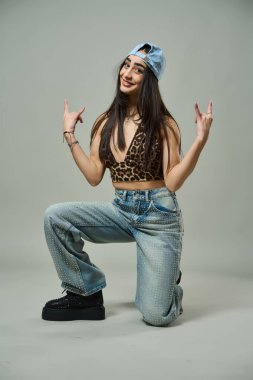 Leopar desenli bluz, yapay elmas kotlu çekici bir kadın ve kendine güvenen bir ifadeyle çömeliyor.