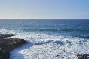 Dalgalar engebeli bir sahil şeridinde kayalıklara çarpıyor. Açık okyanus Tenerife 'de ufka kadar uzanıyor.