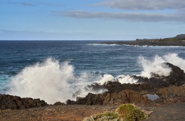 Güçlü okyanus dalgaları volkanik kayalara çarpıyor, Tenerife 'nin engebeli kıyı şeridinde dramatik bir püskürme yaratıyor.