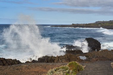 Güçlü okyanus dalgaları volkanik kayalara çarpıyor, Tenerife 'nin engebeli kıyı şeridinde dramatik bir püskürme yaratıyor.
