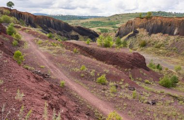 Çürümüş kırmızı volkanik arazi engebeli uçurumlar ve seyrek bitki örtüsü arasında yürüyüş yolu.