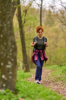 Bir bahar günü ormanda yalnız başına yürüyüş yapan bir kadının portresi.