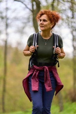 Bir bahar günü sessiz bir orman patikasında yalnız başına yürüyüş yapan bir kadın.