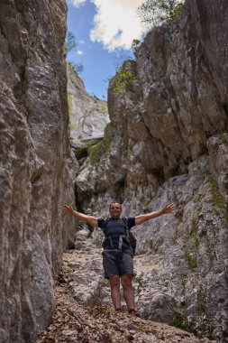 Yüksek kayalık duvarlarla çevrili dik bir kireç taşından vadide uzanmış kolları olan bir adam.