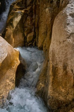 Dar kayalık kireçtaşı vadisinden köpüklü suyla akan güçlü dağ akıntısı.