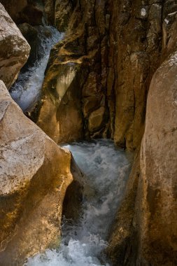 Dar kayalık kireçtaşı vadisinden köpüklü suyla akan güçlü dağ akıntısı.