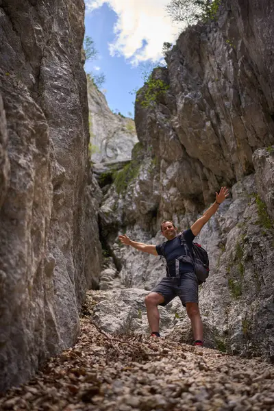 Yüksek kayalık duvarlarla çevrili dik bir kireç taşından vadide uzanmış kolları olan bir adam.
