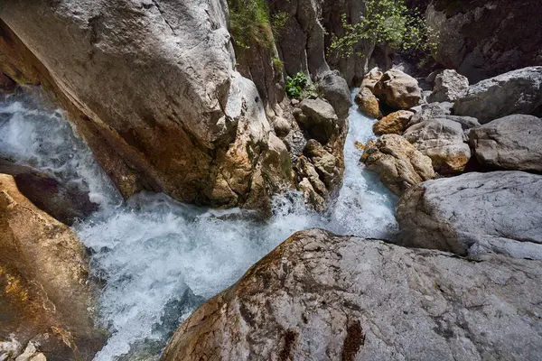Dik taş oluşumlarından akan suyla dar kayalık vadi.