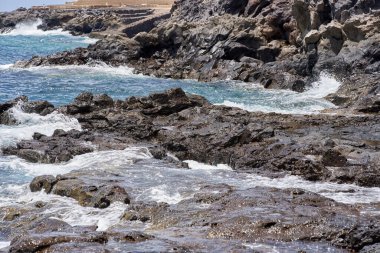 Okyanus dalgası Tenerife 'deki Playa de Montana Amarilla' da volkanik kayalara çarpıyor. 