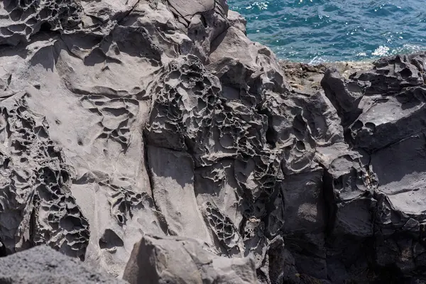 Tenerife 'deki Playa de Montana Amarilla' da okyanus kenarında aşınmış delikleri olan yıpranmış volkanik kayalara yakın çekim