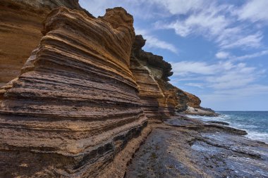 Playa de Montana Amarilla, Tenerife 'de Atlantik Okyanusu' yla buluşan katmanlı kumtaşı kayalıkları