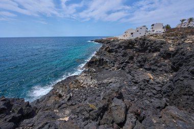 Tenerife 'deki Playa de Montana Amarilla yakınlarında volkanik kıyı şeridi ve okyanus dalgaları çarpışıyor. 