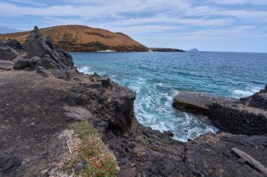 Tenerife 'deki Playa de Montana Amarilla yakınlarında volkanik kıyı şeridi ve okyanus dalgaları çarpışıyor. 
