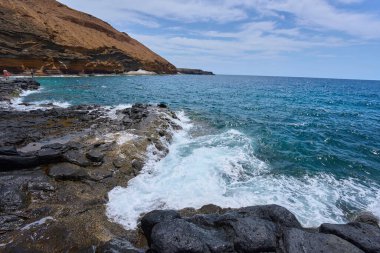 Tenerife 'deki Playa de Montana Amarilla yakınlarında volkanik kıyı şeridi ve okyanus dalgaları çarpışıyor. 