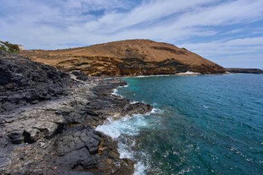 Tenerife 'deki Playa de Montana Amarilla yakınlarında volkanik kıyı şeridi ve okyanus dalgaları çarpışıyor. 