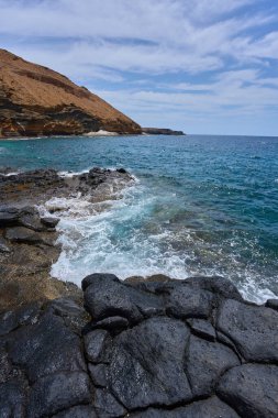 Tenerife 'deki Playa de Montana Amarilla yakınlarında volkanik kıyı şeridi ve okyanus dalgaları çarpışıyor. 