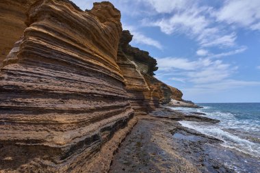 Tenerife 'deki Playa de Montana Amarilla' da okyanusun üzerindeki volkanik kayalıklar.