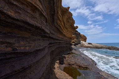 Tenerife 'deki Playa de Montana Amarilla' da okyanusun üzerindeki volkanik kayalıklar.