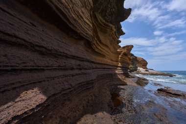 Tenerife 'deki Playa de Montana Amarilla' da okyanusun üzerindeki volkanik kayalıklar.