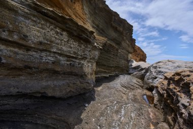 Tenerife 'deki Playa de Montana Amarilla' da okyanusun üzerindeki volkanik kayalıklar.