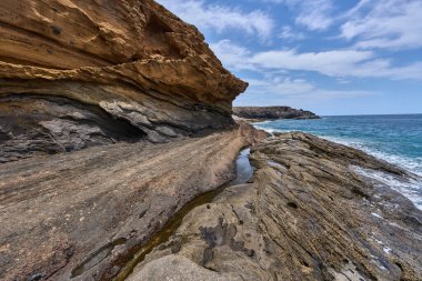 Tenerife 'deki Playa de Montana Amarilla' da okyanusun üzerindeki volkanik kayalıklar.
